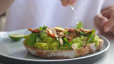 Close up of hand squeezing lime over avocado toast. Healthy vegan breakfast Video stock 151737802