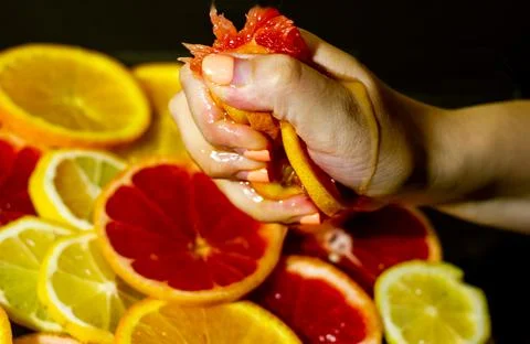 Close up of a hand squeezing a slice of orange Stock Photos