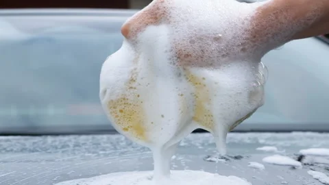Close-up of a hand squeezing a soapy sponge over a car Stock Footage 340627172