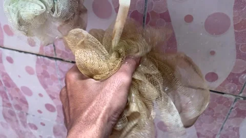 Close-up of Hand Squeezing Wet Synthetic Bath Loofah in Shower Stock Footage 318575287
