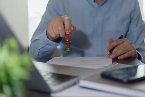 Close-up of hand stamping document with pen in hand. Concept of contract ag.. Stock Photos