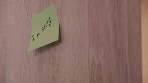Close-up of hand sticking I'm sorry apology sticker on wooden panel. Video Stock Footage 335553125