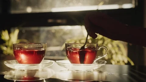 Close up of hand stirring hot red tea in glass cup with saucer on reflectiv.. Stock-Footage 334981235