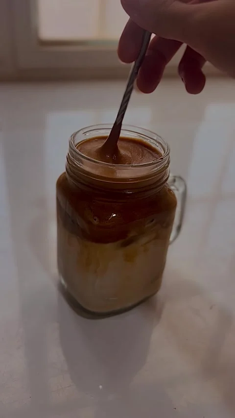 Close-up of hand stirring iced coffee in a glass jar Vídeos de archivo 336136985