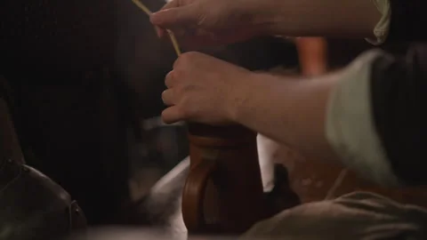 Close up of hand stirring steaming drink in rustic ceramic mug on table with Vidéo 347080397