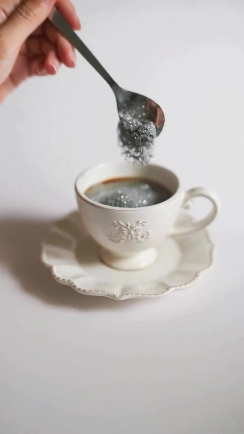 Close-up of hand stirring sugar into a coffee cup for a cozy morning Video stock 343906799