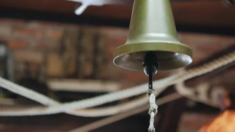 A close-up hand strikes an old ship's bell Stock Footage 132028480
