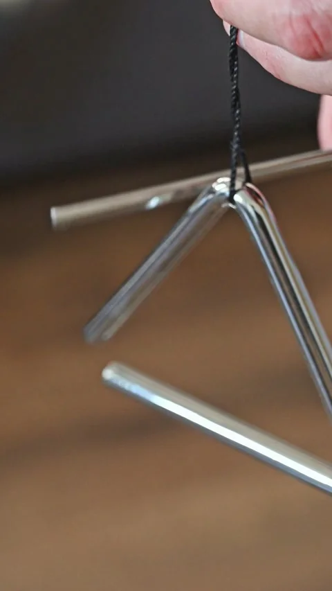Close-up of Hand Striking a Metal Triangle Percussion Instrument Stock Footage 332907591