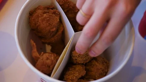 The close up hand takes a piece of fried chicken on the dish. fast food Vidéo 75910540