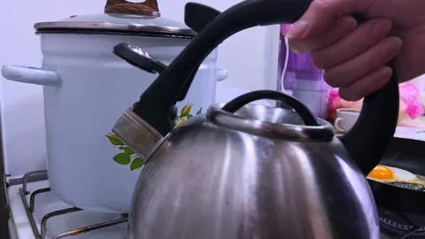 Close Up Hand Taking Boiling Kettle Off Stove in Kitchen Stock Footage 329754992