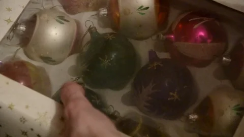 Close up of hand taking out shiny aged Christmas speheres from box Stock Footage 70333086