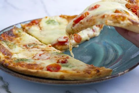 Close-up of hand taking a slice of pizza Stock Photos
