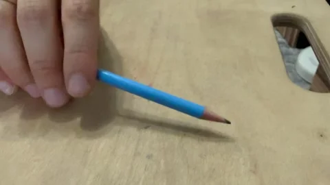 Close-up of hand tapping a blue pencil rhythmically on a wooden surface Stock Footage 336524189