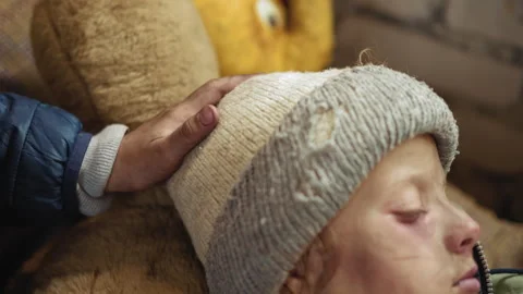 Close Up of Hand Tapping Head of Sick Boy Resting in Worn Hat 動画素材 329463725