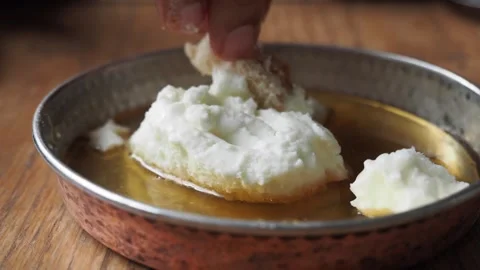 Close-up hand tearing bread and dipping into honey and cream dish for a tra.. Video stock 332578325