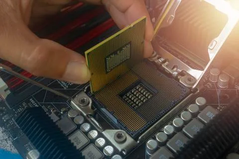 Close up hand of technician putting CPU on the socket of computer motherboard Stock Photos
