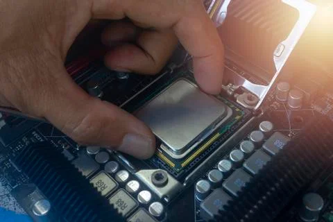 Close up hand of technician putting CPU on the socket of computer motherboard Stock Photos