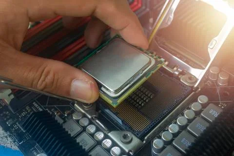 Close up hand of technician putting CPU on the socket of computer motherboard Stock Photos