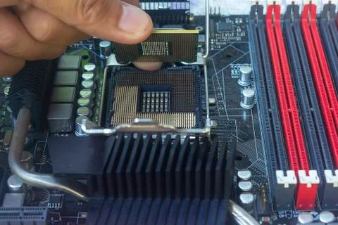 Close up hand of technician putting CPU on the socket of computer motherboard Stock Photos