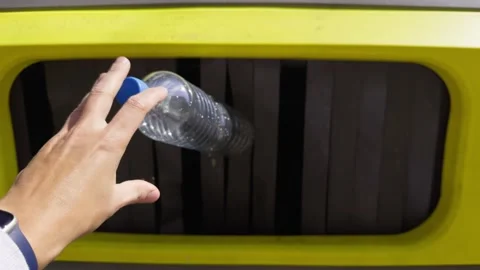 Close-up of a hand throwing empty plastic bottles into the recycling bin. Stock Footage 335693338