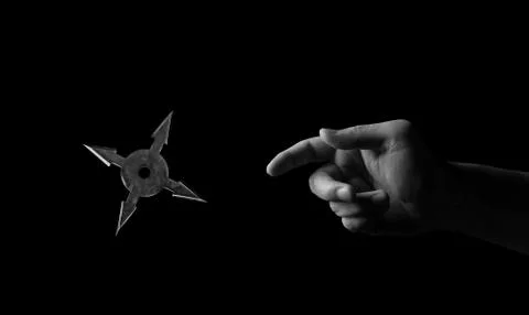 Close up Hand Throwing Ninja Star Shuriken Isolated on Black Background, Blac Photos