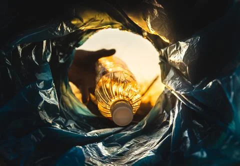 Close-up of a hand throwing a plastic bottle into the trash can. Close-up of the Stock Photos