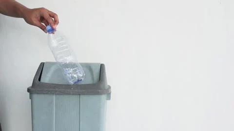 Close-up of a hand throwing a used bottle into a trash can. Video stock 337393364