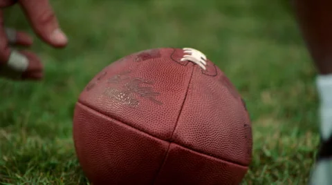 Close-up hand tilting a football on grass Stock Footage 59264397
