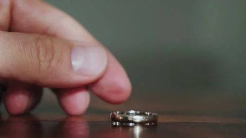 Close-up of hand tossing a wedding ring on a table. Betrayal and divorce concept Video stock 303926893