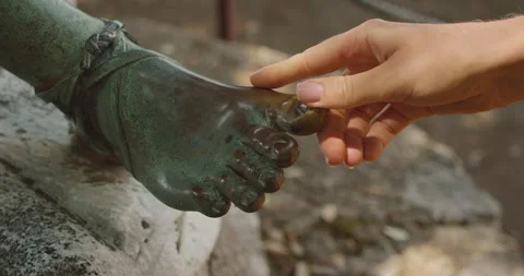 Close-up of a hand touching the bronze foot of a statue, symbolizing good luck Stock Footage 276452104