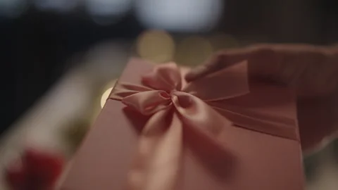 Close-up of hand touching festive gift box with large bow, celebrating holidays Stock Footage 323346958