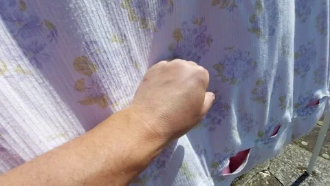 Close-up of hand touching soft purple floral fabric on a clothesline Vídeos de archivo 334567565