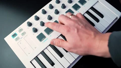 Close-up hand triggers drum pads and tweaks knobs on a MIDI controller Stock-Footage 331157507