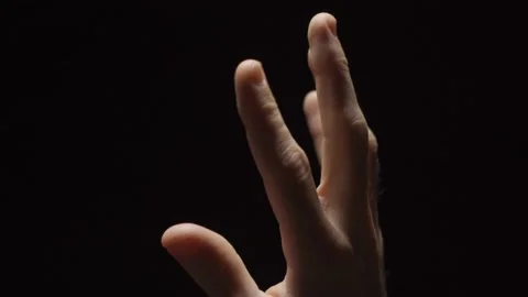 Close up - hand trying to reach touch or get closer to light - darkness in bg Stock Footage 132259751