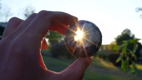 Close-Up of Hand Turning 3D Globe Puzzle Catching Sun Rays Stock Footage 295116304
