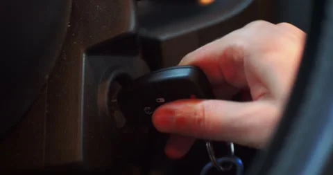 Close-up of a hand turning a car key in the ignition, starting the engine... Stockbeeldmateriaal 319882457