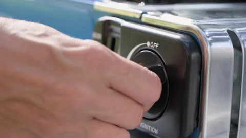 Close up of a hand turning the ignition dial on a portable camping gas stove Stock Footage 339093587