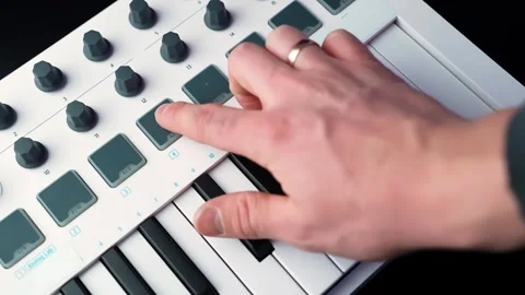Close-up of a hand turning a knob on a compact MIDI keyboard controller with Stockbeeldmateriaal 328586448