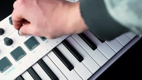 Close-up of a hand turning a knob on a compact MIDI keyboard controller Stockbeeldmateriaal 328871259