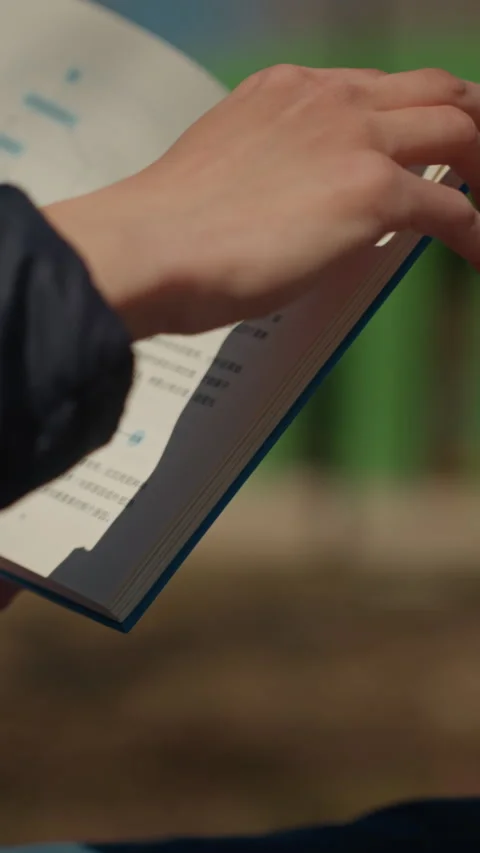 Close up hand turning open diagram book pages in soft indoor lighting featuring Stock Footage 345046468