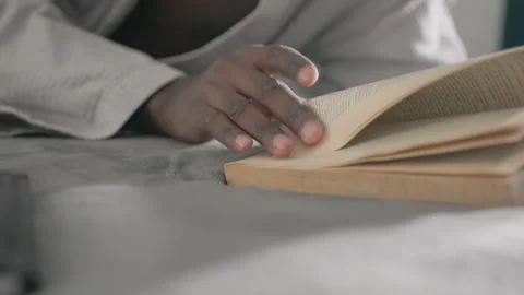 Close-up of hand turning pages of book while lying on bed in peaceful indoor Stock Footage 317201466
