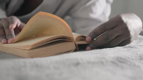 Close-up of hand turning pages of large book while lying on bed in peaceful Stock Footage 317201236