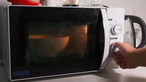 Close-up of a hand turning the rotary knob to start a microwave oven, setting Stock Footage 333649359