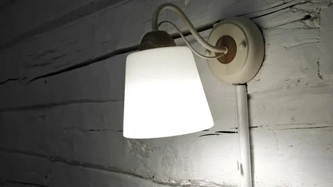 Close-up hand turning on a wall lamp light clicking a rope control. Switches on Stock Footage 326777434