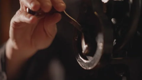 Close up hand turning wheel of antique sewing machine, careful oiling and gear Stock Footage 346549823