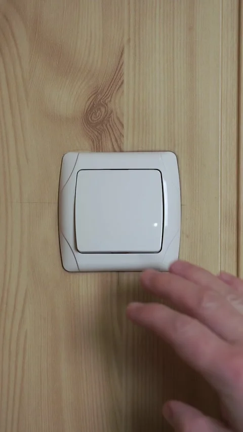 Close up of hand turning white light switch on and off on wooden background Stock Footage 305250340
