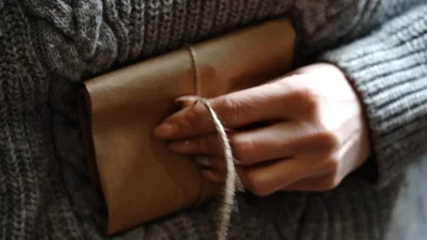 Close-Up Hand Tying Knot on Wrapped Leather Wallet Held Against Body Stock Footage 315528600