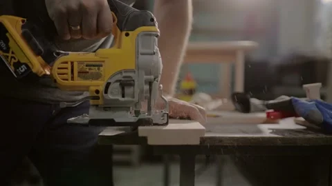 Close up on hand of unknown carpenter working with an electric jigsaw cutting wo Stock Footage 219347120