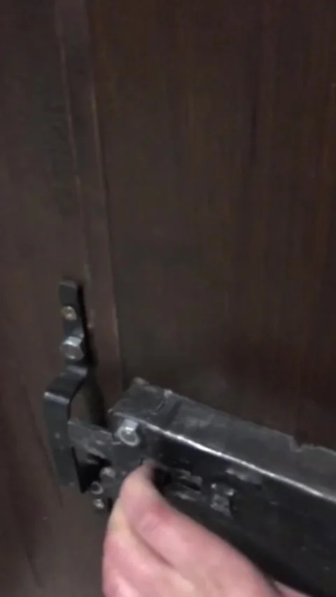 Close-up of a hand unlocking a heavy, rustic wooden door with an old metal latch Stock-Footage 333376806
