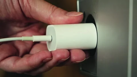 Close up of hand unplugging charger from wall outlet, electricity usage and Stock Footage 334943912